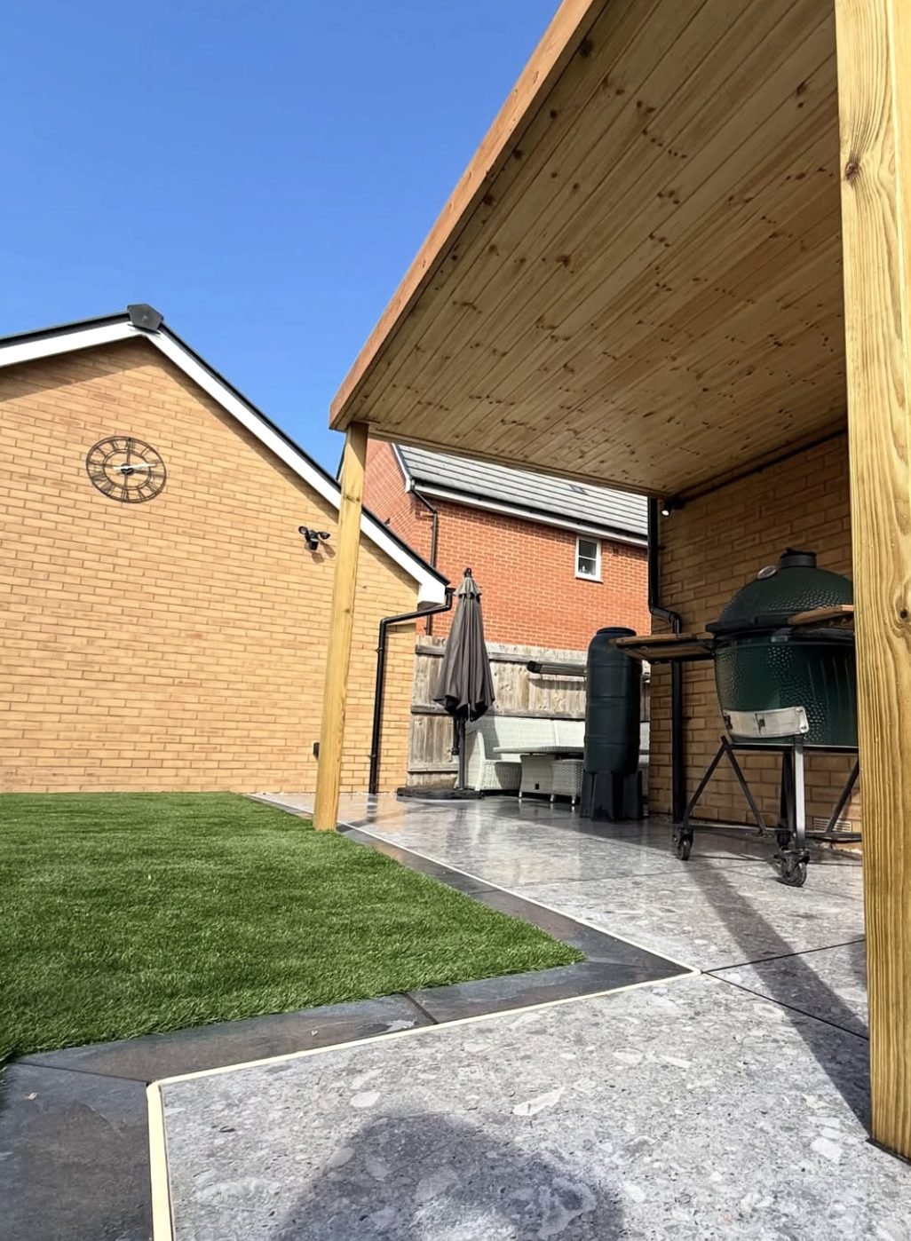 Artificial lawn and outdoor kitchen area under timber pergola